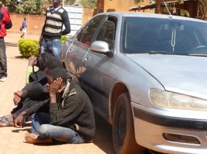 Les cyberdélinquants présumés (assis) adossés à leur véhicule 406 acquis avec l'argent de leurs forfaits. Photo: Burkina24