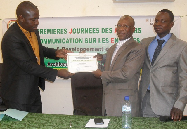 Une attestation de reconnaissance remise au Dr Firmin Gouba (milieu) avec à droite, Grégoire Bazié, président de la JED 