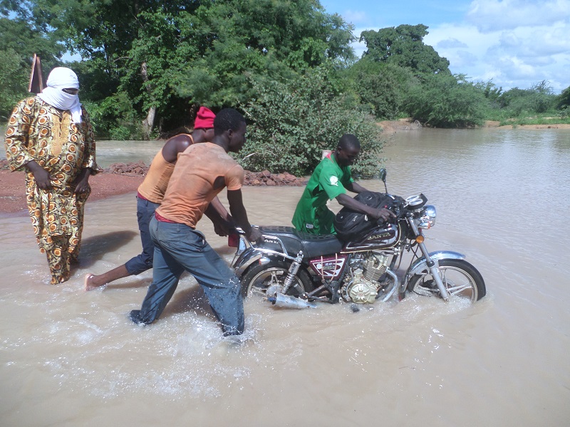 Des jeunes aidant un motocycliste à traverser le pont 