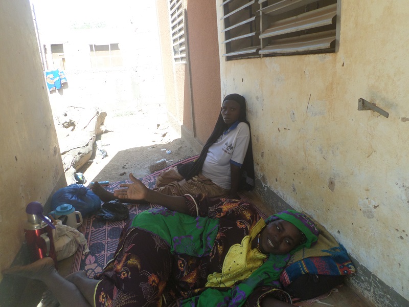 Une femme à terme assise devant la maternité en compagnie de sa belle mère